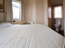 A bedroom with a bed a pillow curtains a window and an ensuite bathroom with a toilet at Hazel Park Lodge HP4 Rhyl