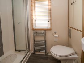 A bathroom with a toilet a shower a window with blinds and a towel radiator at Hazel Park Lodge HP4 in Rhyl