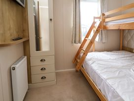A bedroom with a wooden bunk bed a wardrobe with a mirror and a radiator at Hazel Park Lodge HP4 in Rhyl