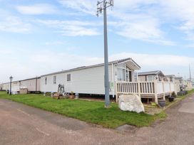 A row of caravans with a fenced porch on a grassy area at Hazel Park Lodge HP4 in Rhyl