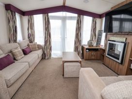 A living room with sofas a coffee table a wall-mounted television and a fireplace at Hazel Park 11 HP11 in Rhyl