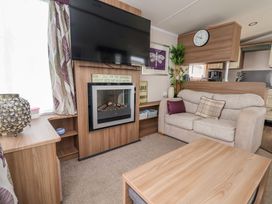 A living room with a sofa cushions fireplace tv and a wooden coffee table at Hazel Park 11 HP11 in Rhyl