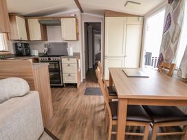 A kitchen and dining area with wooden furniture and appliances at Hazel Park 11 HP11 in Rhyl