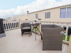 An outdoor deck with two wicker chairs and a small round table with decorative items on it at Hazel Park 11 HP11 in Rhyl