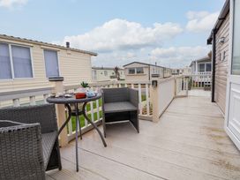 An outdoor deck with two chairs and a small table with decorations at Hazel Park 11 HP11 in Rhyl