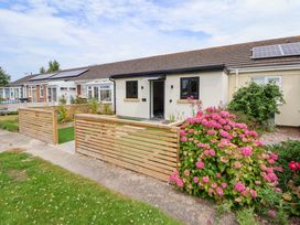 A house with a wooden fence and flowers outside at 4 Willow Grove - Freehold Talacre
