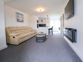 A living room with a sofa and kitchen area at 4 Willow Grove - Freehold in Talacre