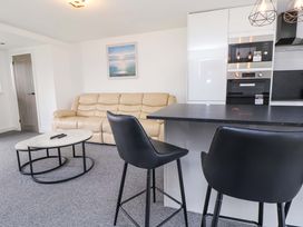 A living room with a sofa, coffee table, and kitchen area at 4 Willow Grove - Freehold Talacre