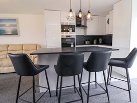 A kitchen with bar stools and appliances at 4 Willow Grove - Freehold in Talacre