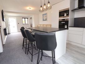 A kitchen with a countertop and bar stools at 4 Willow Grove - Freehold in Talacre
