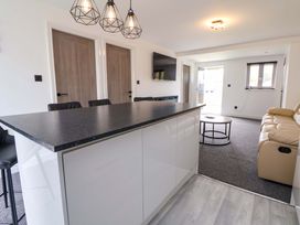 A living room with a kitchen island and sofas at 4 Willow Grove - Freehold Talacre
