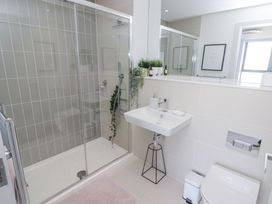 A bathroom with a glass shower enclosure a wall-mounted sink and a toilet at The Links 40 An apartment with spectacular sea views in Porthcawl