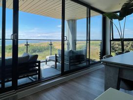A balcony with outdoor seating overlooking a landscape seen through glass doors at The Links 40 in Porthcawl