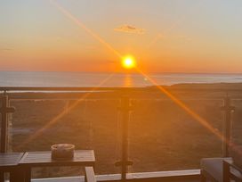 A balcony with a table and a candle holder overlooking the sea at sunset at The Links 40 An apartment with spectacular sea views Porthcawl