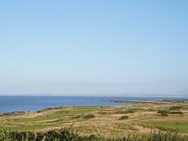 A coastal golf course with grass and bunkers next to the sea at The Links 40 An apartment with spectacular sea views in Porthcawl