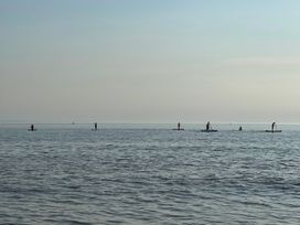 Six people paddleboarding on a calm sea at The Links 40 An apartment with spectacular sea views in Porthcawl