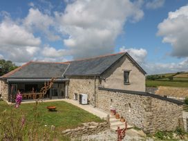 An outdoor view of a stone building with a patio and garden at Reddaway Threshing Barn near Okehampton