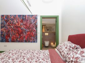 A bedroom with a bed and a bathroom entrance at Reddaway Threshing Barn near Okehampton
