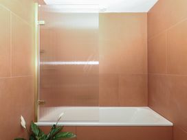 A bathtub with a shower screen and a plant in Reddaway Threshing Barn near Okehampton