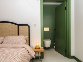 A bedroom with a bed and a green door leading to a toilet at Reddaway Threshing Barn near Okehampton