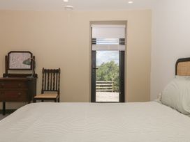 A bedroom with a bed, table, chair and window at Reddaway Threshing Barn near Okehampton