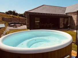 An outdoor area with a hot tub and seating at Reddaway Threshing Barn near Okehampton