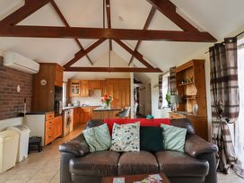 A living room with a sofa and kitchen area at Daisy Cottage in Whitchurch Canonicorum near Charmouth