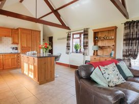 A kitchen with wooden cabinets and a sofa at Daisy Cottage in Whitchurch Canonicorum near Charmouth