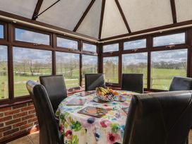 A dining table with chairs and windows in a conservatory at Daisy Cottage in Whitchurch Canonicorum near Charmouth