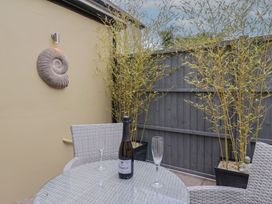 An outdoor seating area with a table, chairs, and a bottle of prosecco at Flat 2 The Cedars in Lyme Regis