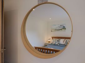 A bedroom with a mirror reflecting a bed and lamp at Flat 2 The Cedars in Lyme Regis