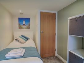 A bedroom with a single bed and a shelf unit at Flat 2 The Cedars Lyme Regis
