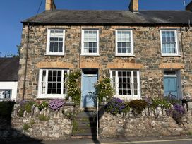 A stone house with a blue door and flower pots at Ty Clyd in Newport, Pembrokeshire