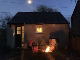 An outdoor scene with a cottage and fire pit at Cwt Mochyn Llanberis