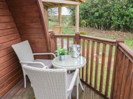 A small wooden balcony with two wicker chairs a round glass table with glasses and a plant at Charlottes Holbeach
