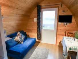 A small wooden room with a blue sofa a door a wall-mounted TV and a table with a plant at Charlottes in Holbeach