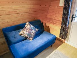A blue sofa with two cushions next to a wooden wall and a door with patterned curtains at Charlottes in Holbeach