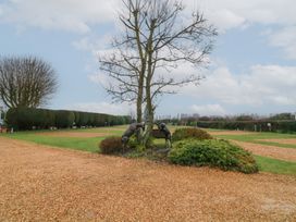 A garden with a tree and two deer statues surrounded by trimmed bushes and gravel paths at Charlottes in Holbeach