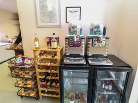 A beverage station with wine bottles on a rack beer dispensers on refrigerators and snacks on shelves at Charlottes in Holbeach