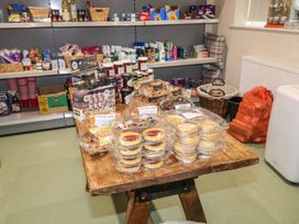 A display table with packaged cakes jams and crackers near shelves with toiletries and food items at Charlottes in Holbeach