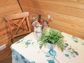 A wooden chair next to a table with a floral tablecloth a metal bucket holding a wine bottle and two wine glasses and a small metal pot with a green plant at Charlottes in Holbeach