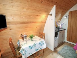 A small dining area with a table and two wooden chairs next to a kitchenette with flowers and a sink at Charlottes in Holbeach