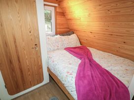 A small bedroom with wooden walls a bed with floral bedding and a pink blanket at Charlottes Holbeach