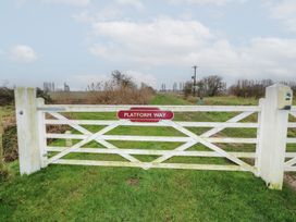 A white gate with a Platform Way sign in a grassy rural area at Charlottes in Holbeach