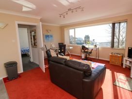 A living room with a brown leather sofa a glass dining table and a desk with a chair by a large window showing a city view at Rosa in Torquay
