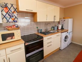 A kitchen with a microwave oven stove sink washing machine and refrigerator at Rosa in Torquay