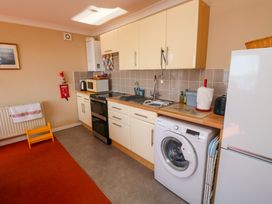 A kitchen with cream cabinets a washing machine a refrigerator stove microwave and various kitchen items at Rosa in Torquay