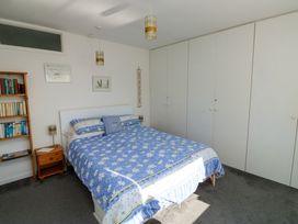 A bedroom with a double bed with blue floral bedding a wooden bookshelf and a large built in wardrobe at Rosa in Torquay