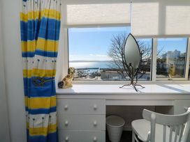 A desk with a mirror and a ceramic dog figurine by a window with blinds and striped curtains at Rosa in Torquay