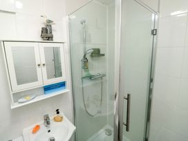 A bathroom with a sink, a mirror cabinet, a soap dispenser, a shower enclosure with a glass door and a showerhead at Rosa in Torquay